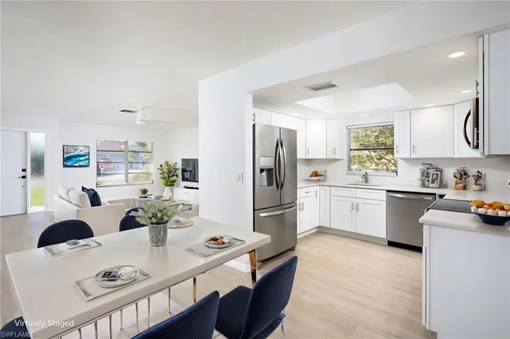 Kitchen with light  quartz countertops, stainless steel appliances, light wood-style floors, white cabinetry, and recessed lighting
