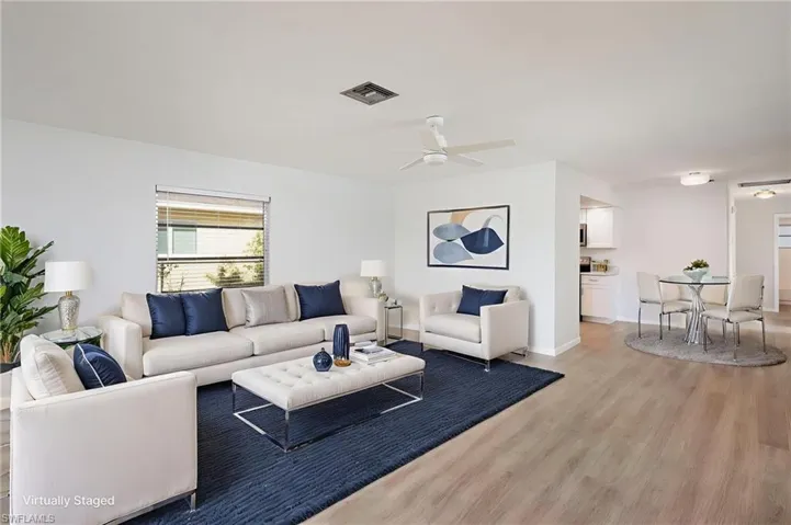 Living room with light wood-style flooring and new light/ceiling fan