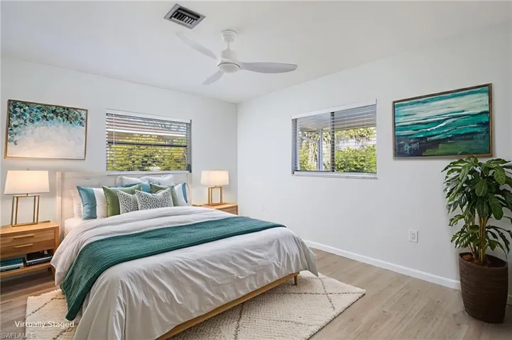 Bedroom featuring multiple windows, light wood-style floors, and a new light/ceiling fan