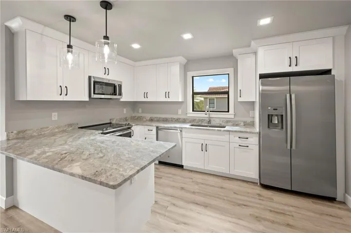 Kitchen with white cabinets, light hardwood / wood-style floors, appliances with stainless steel finishes, and sink