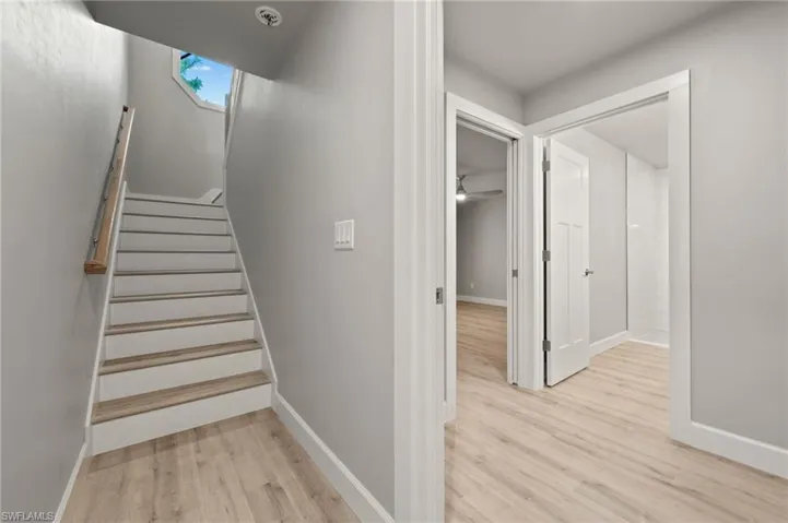 Stairway with light wood-type flooring and ceiling fan