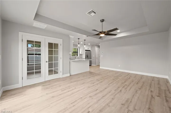 Unfurnished living room featuring french doors, ceiling fan, a raised ceiling, and light hardwood / wood-style floors