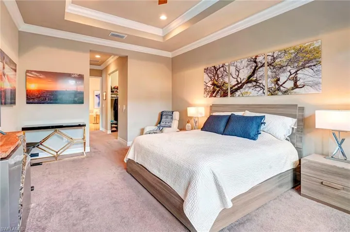 Carpeted bedroom featuring a tray ceiling and ornamental molding