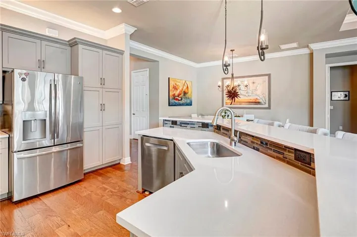 Kitchen with sink, ornamental molding, appliances with stainless steel finishes, and light hardwood / wood-style floors