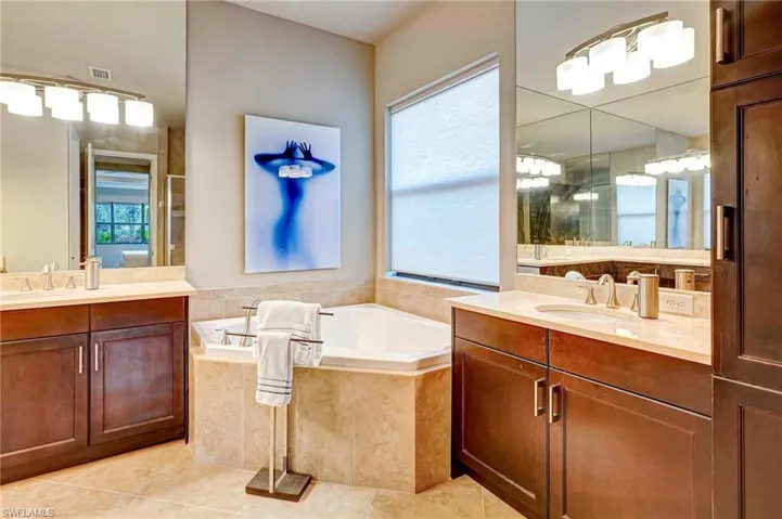Main Bathroom featuring tile patterned floors, a wealth of natural light, vanity, and a relaxing tiled tub