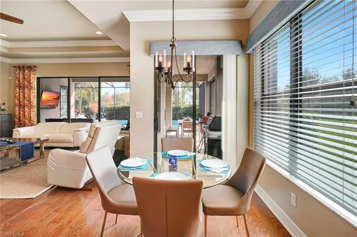 Dining space with a notable chandelier, crown molding, a tray ceiling, and hardwood / wood-style floors