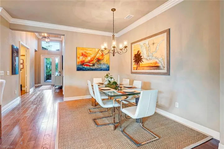 Dining area featuring hardwood / wood-style flooring, crown molding, and a chandelier