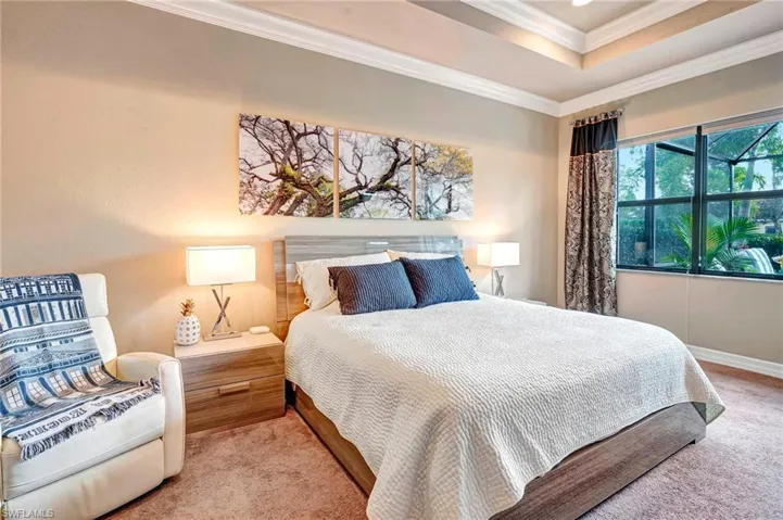 Bedroom featuring a raised ceiling, crown molding, and carpet floors