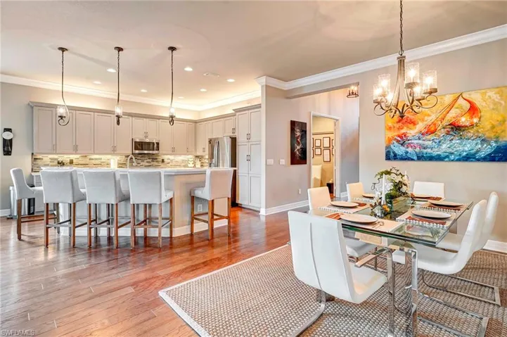 Dining room featuring sink, ornamental molding, light hardwood / wood-style floors, and an inviting chandelier