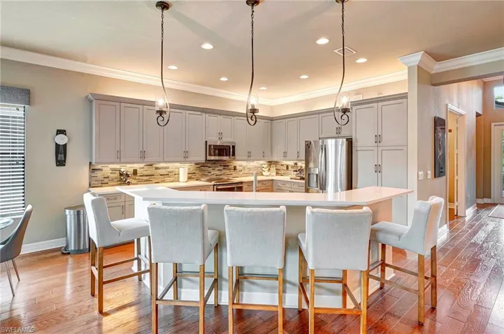 Kitchen with light hardwood / wood-style floors, appliances with stainless steel finishes, a breakfast bar area, and a spacious island