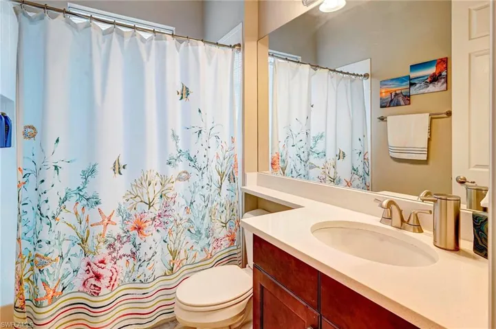 Bathroom with toilet, vanity, and curtained shower