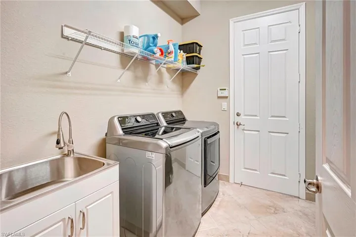 Clothes washing area with sink, cabinets, and separate washer and dryer