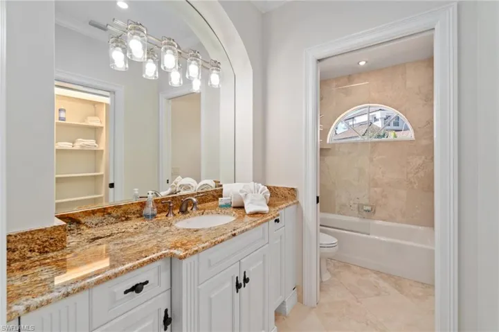 Bathroom featuring toilet, vanity, tub / shower combination, crown molding, and tile patterned floors