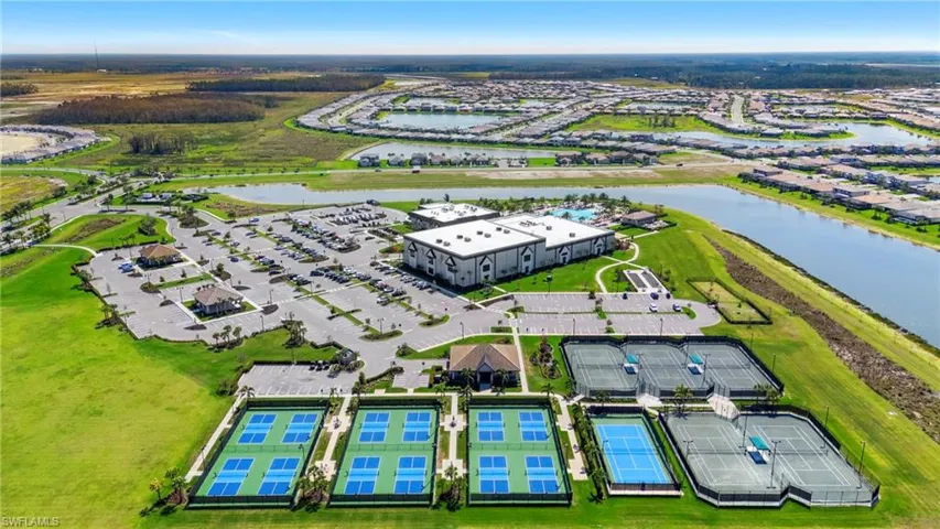 Expansive recreational complex featuring multiple sports courts, a large parking area, and a substantial clubhouse with an outdoor pool