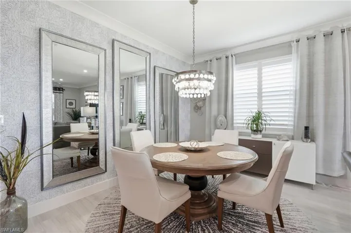 Elegant dining room featuring a round pedestal table, four upholstered chairs, and a crystal chandelier suspended from a coffered ceiling