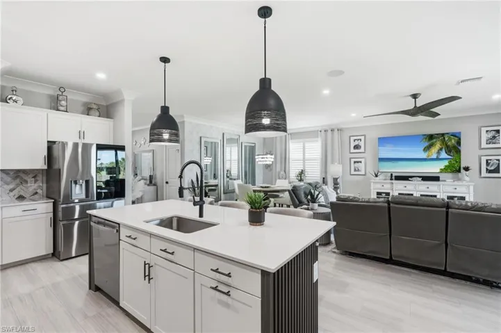 Open-concept living area with light wood-finish flooring, white cabinetry, and stainless steel appliances