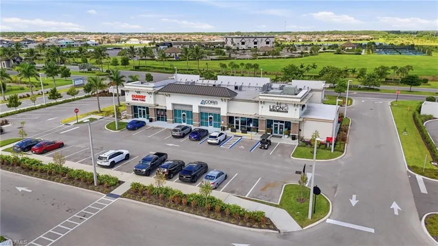Commercial building with multiple storefronts, ample paved parking, and visible signage