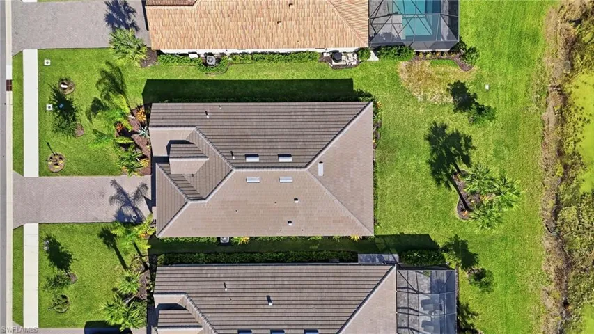 Aerial view showcasing two residences with architectural rooflines featuring multiple peaks and dormers, dark shingle finishes, and integrated guttering