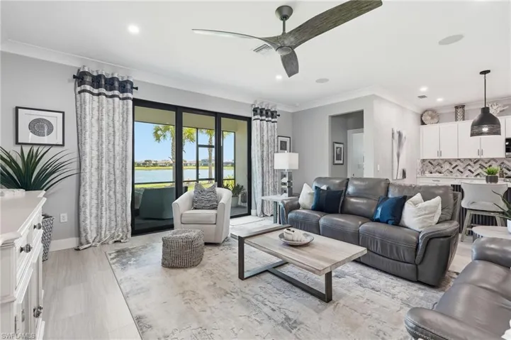 Sophisticated open-concept living space featuring a gray upholstered sectional, light wood-finish flooring, and a neutral area rug anchoring the seating arrangement