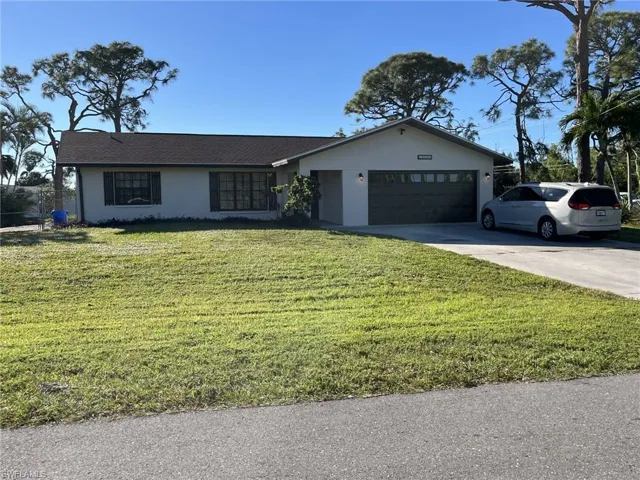 Single story home with a garage and a front lawn