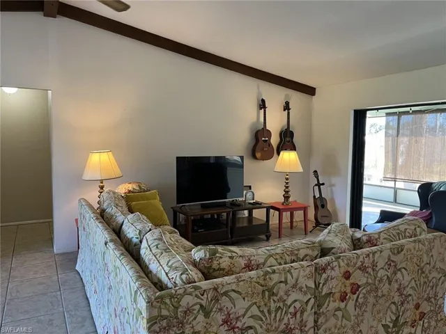 Living room with vaulted ceiling with beams and light tile patterned floors