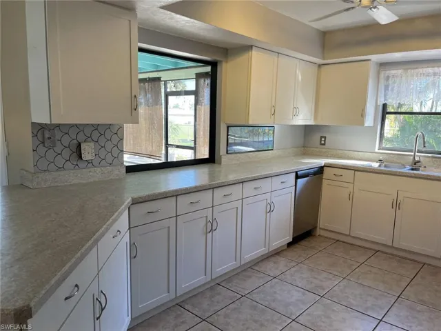 Kitchen featuring a wealth of natural light, dishwasher, white cabinets, and sink