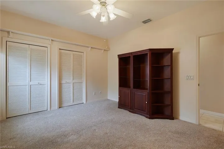 Unfurnished bedroom with carpet flooring, multiple closets, a ceiling fan, and baseboards