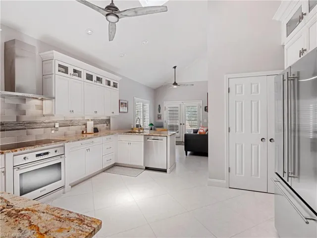 Kitchen with kitchen peninsula, appliances with stainless steel finishes, ceiling fan, and wall chimney range hood