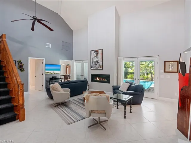 Tiled living room with high vaulted ceiling, french doors, and ceiling fan