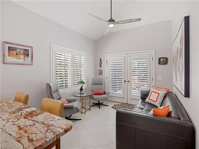 Living room featuring french doors, light tile patterned flooring, ceiling fan, and vaulted ceiling