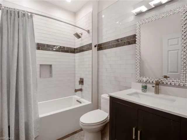Full bathroom featuring toilet, vanity, and shower / tub combo with curtain