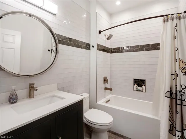 Full bathroom with shower / tub combo, tile walls, decorative backsplash, toilet, and vanity