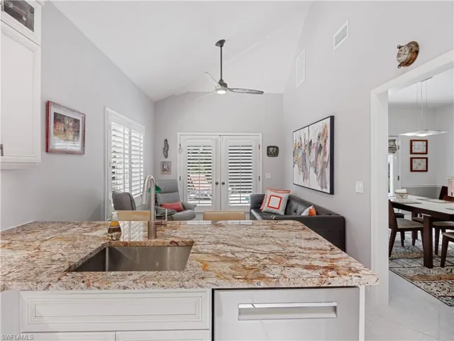 Kitchen with white cabinetry, ceiling fan, sink, light stone countertops, and light tile patterned floors