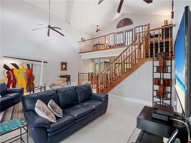 Tiled living room featuring ceiling fan and high vaulted ceiling
