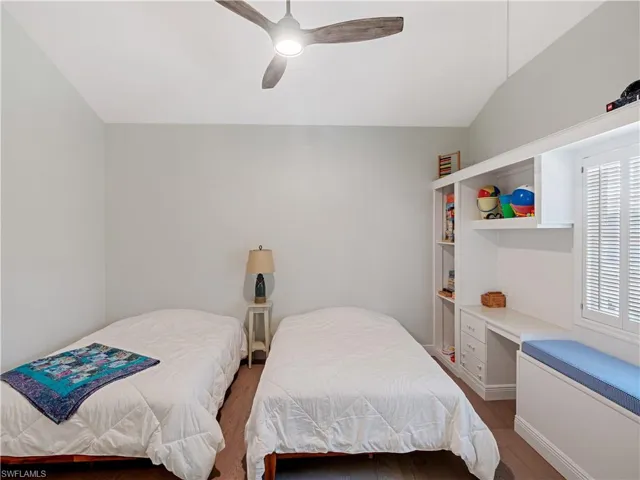 Bedroom with hardwood / wood-style floors, multiple windows, ceiling fan, and vaulted ceiling