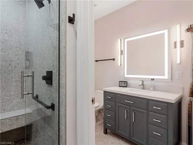 Bathroom with vanity, walk in shower, tile patterned flooring, and toilet