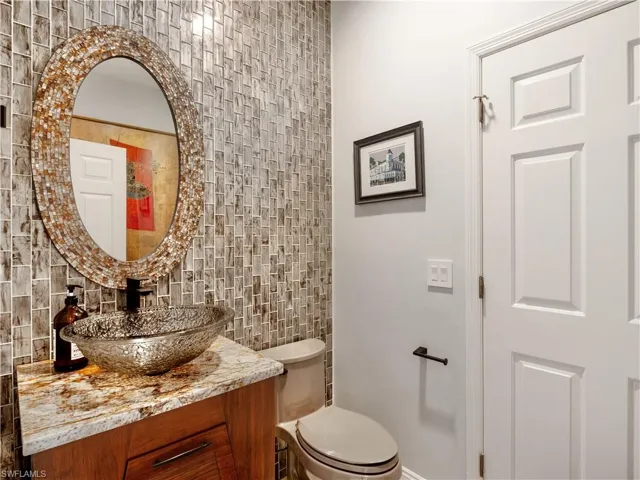 Bathroom with vanity, toilet, tasteful backsplash, and tile walls
