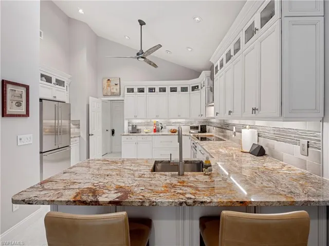 Kitchen featuring ceiling fan, white cabinets, sink, high end refrigerator, and backsplash