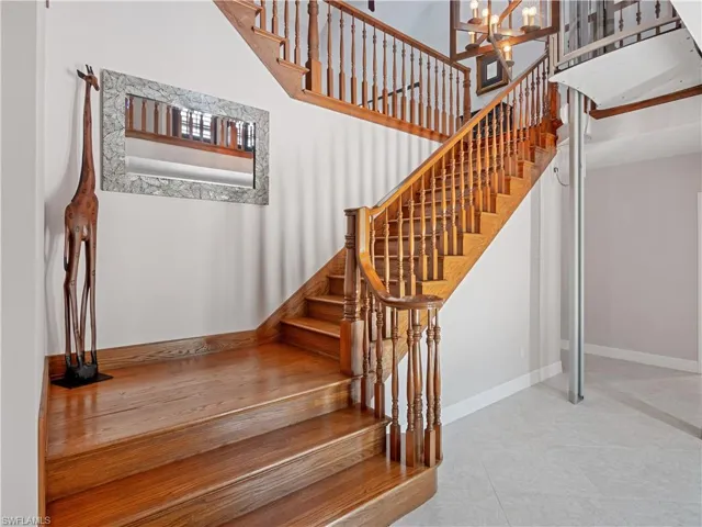 Staircase with an inviting chandelier, tile patterned floors, and a towering ceiling