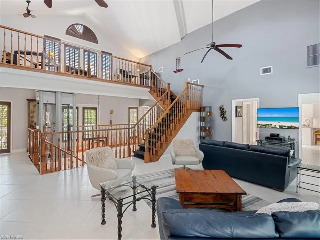 Living room with high vaulted ceiling, ceiling fan, and a wealth of natural light