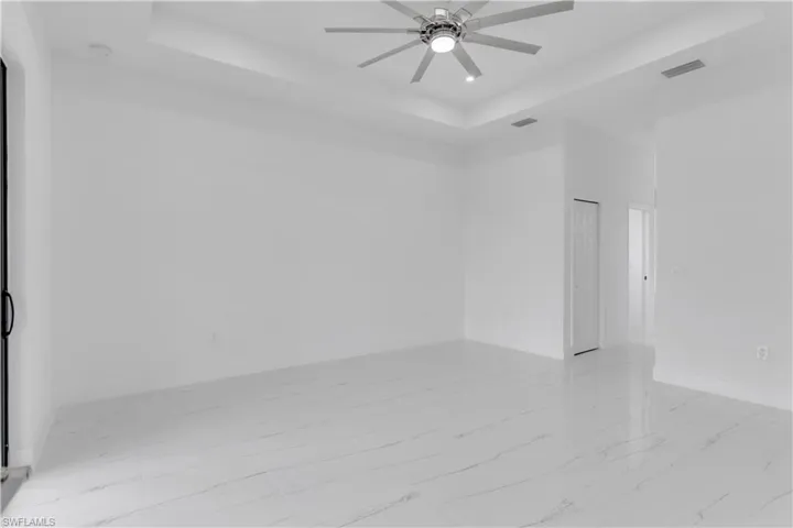 Empty room with ceiling fan and a raised ceiling