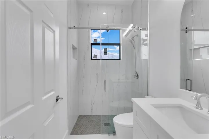 Bathroom featuring toilet, a shower with shower door, and vanity