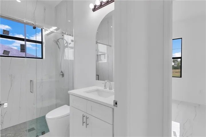 Bathroom featuring a healthy amount of sunlight, vanity, toilet, and walk in shower