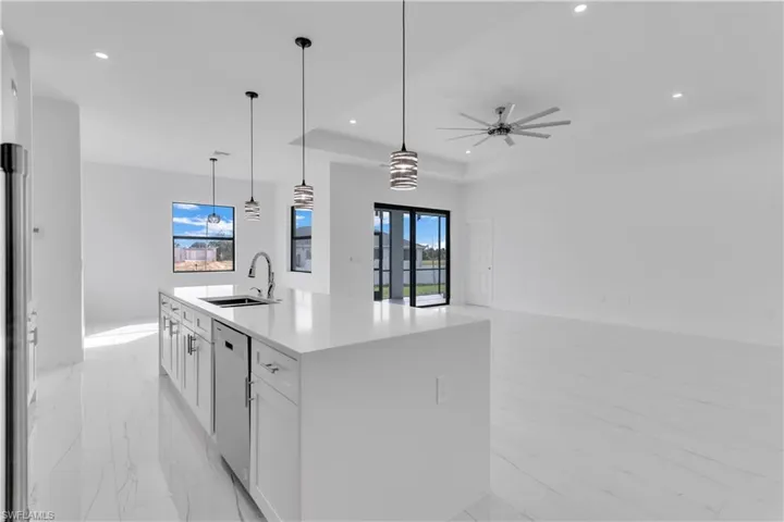 Kitchen featuring sink, white cabinets, a kitchen island with sink, and plenty of natural light
