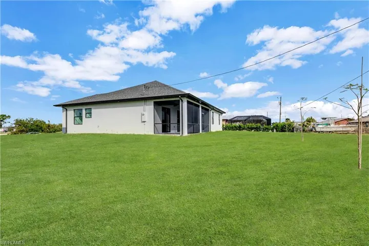 Rear view of house with a sunroom and a lawn