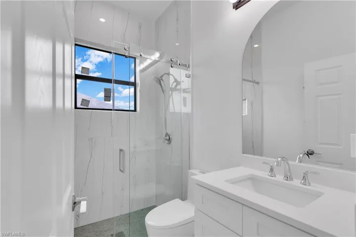 Bathroom featuring toilet, an enclosed shower, and vanity