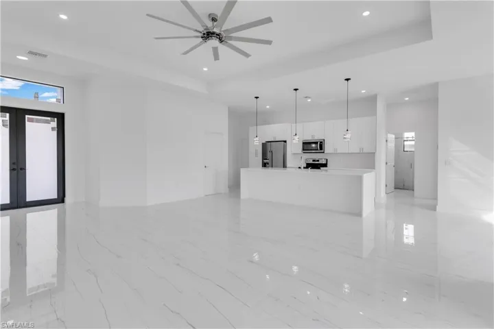 Unfurnished living room with french doors, ceiling fan, and a raised ceiling