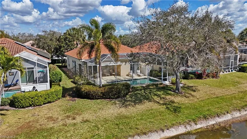 Back of house with a sunroom, an outdoor pool, a lawn, a patio, and glass enclosure