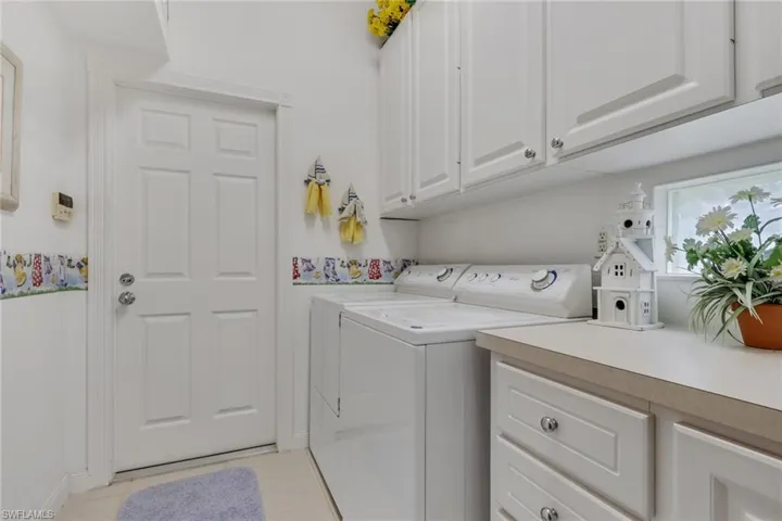 Laundry room featuring separate washer and dryer, light tile patterned floors, and cabinet space