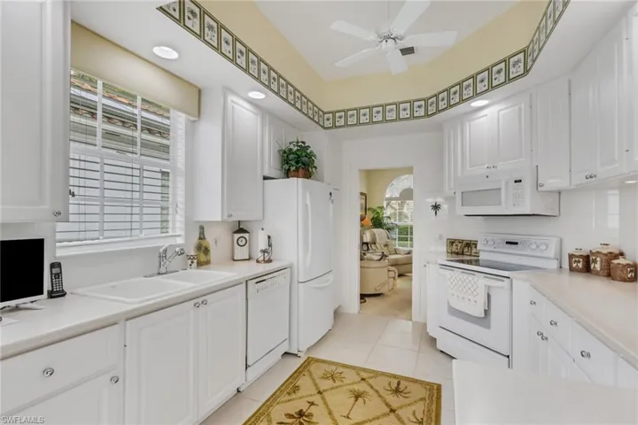 Kitchen featuring white appliances, light countertops, white cabinetry, and a ceiling fan